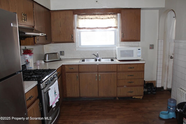 kitchen featuring dark wood-style floors, a sink, light countertops, under cabinet range hood, and appliances with stainless steel finishes