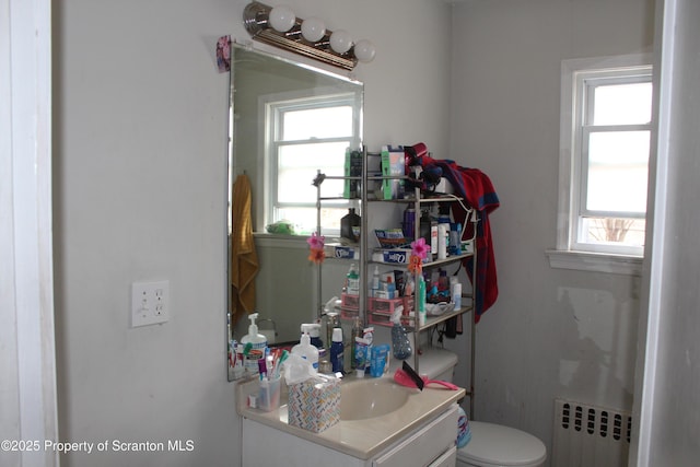 half bath featuring vanity, radiator heating unit, and toilet