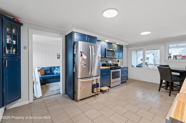 kitchen with ornamental molding, stainless steel appliances, and blue cabinets