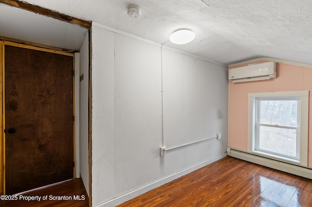 spare room featuring a baseboard heating unit, wood-type flooring, a wall unit AC, and a textured ceiling