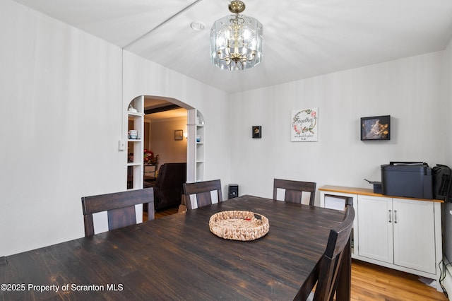 dining area with a notable chandelier and light hardwood / wood-style flooring