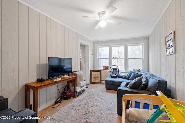 living room with light carpet, ceiling fan, and wood walls