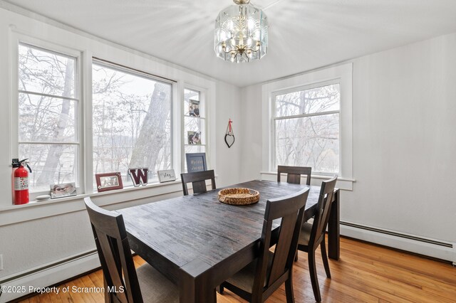 dining room with a baseboard heating unit, an inviting chandelier, and light hardwood / wood-style flooring