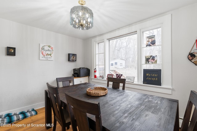 dining room featuring wood-type flooring, a notable chandelier, and a fireplace