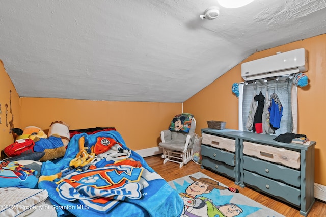 bedroom with an AC wall unit, hardwood / wood-style floors, lofted ceiling, and a textured ceiling