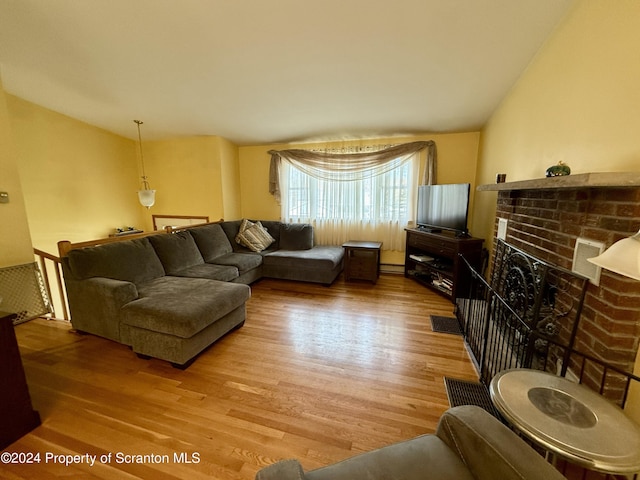 living room featuring a fireplace, a baseboard radiator, wood-type flooring, and lofted ceiling