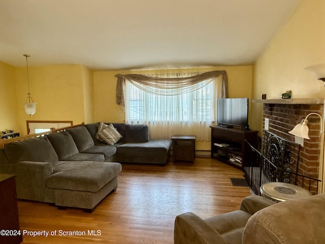 living room with a fireplace, hardwood / wood-style floors, a baseboard radiator, and lofted ceiling