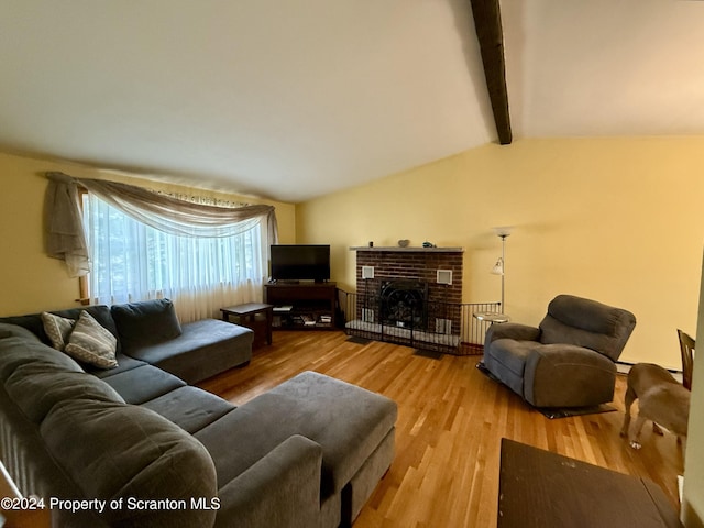 living room featuring hardwood / wood-style floors, vaulted ceiling with beams, and a brick fireplace