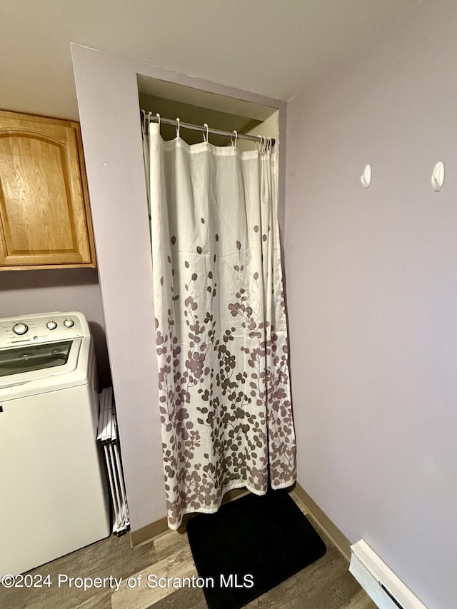 bathroom with hardwood / wood-style flooring, washer / clothes dryer, and a baseboard heating unit