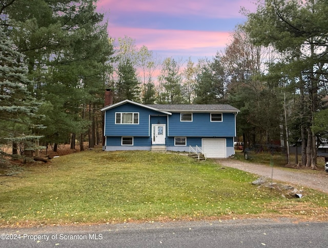 bi-level home featuring a garage and a lawn