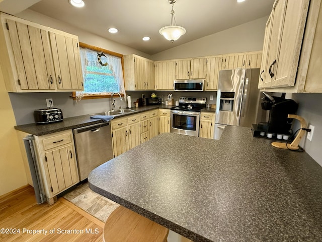 kitchen featuring sink, stainless steel appliances, kitchen peninsula, lofted ceiling, and light brown cabinetry