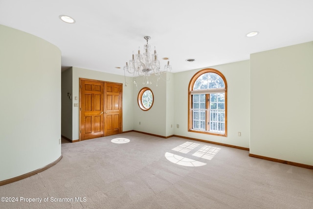 empty room with light carpet and an inviting chandelier