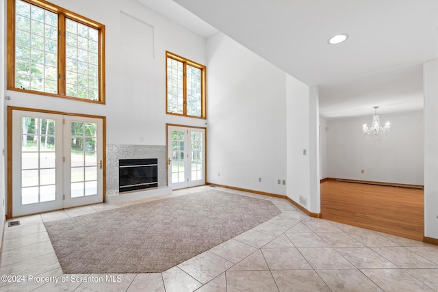 unfurnished living room with light tile patterned floors, an inviting chandelier, and french doors