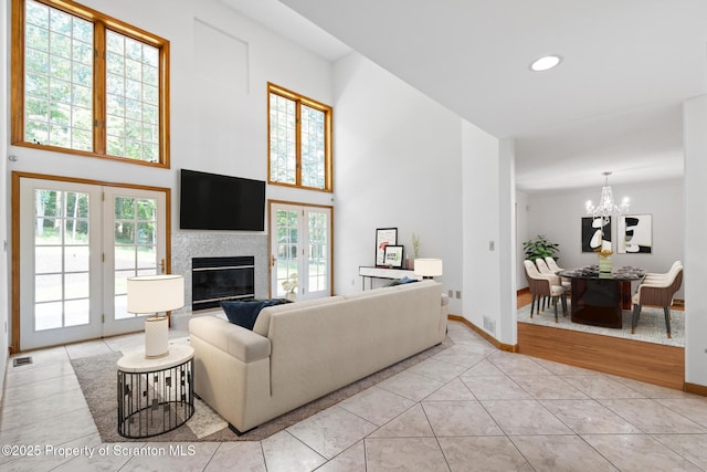 133 Glenmaura Dr, Moosic, PA 18507 - living room featuring a chandelier, a towering ceiling, baseboards, a glass covered fireplace, and light tile patterned floors
