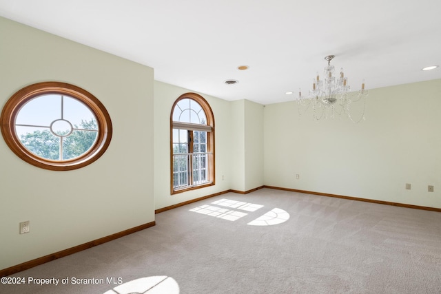 carpeted empty room featuring a chandelier