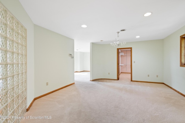 unfurnished room featuring a chandelier and light colored carpet