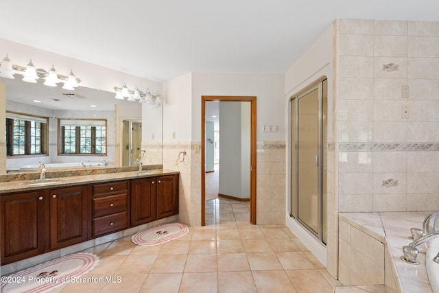 bathroom with tile patterned floors, separate shower and tub, vanity, and tile walls