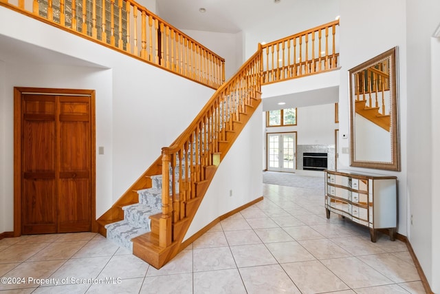 stairs with tile patterned floors and a towering ceiling