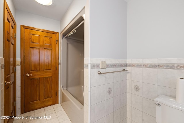 bathroom featuring tile patterned floors, toilet, tile walls, and bath / shower combo with glass door