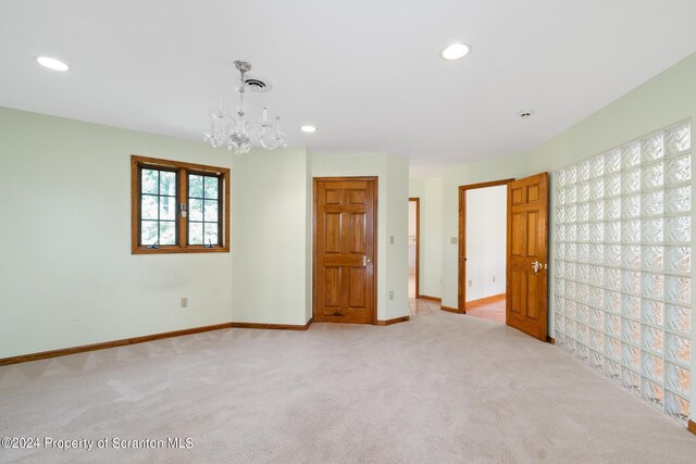 carpeted spare room with a notable chandelier