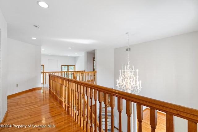 corridor with a chandelier and light hardwood / wood-style floors