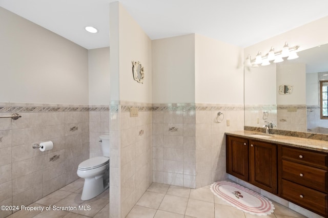 bathroom with tile patterned flooring, vanity, toilet, and tile walls