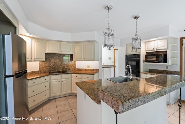 kitchen with hanging light fixtures, sink, light tile patterned floors, and black appliances