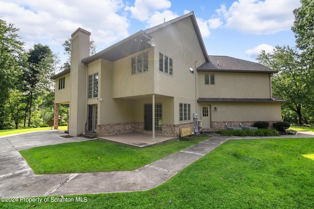 133 Glenmaura Dr, Moosic, PA 18507 - rear view of house featuring stucco siding, a chimney, a lawn, and brick siding