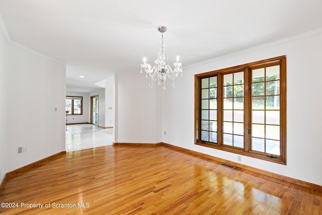 unfurnished room with light hardwood / wood-style floors, ornamental molding, and a notable chandelier