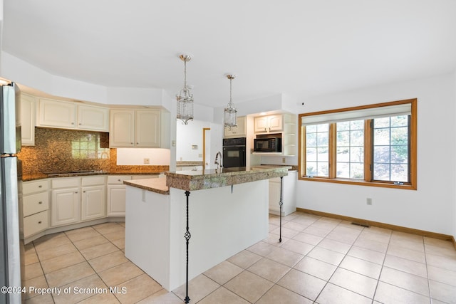 kitchen featuring a center island with sink, black appliances, decorative backsplash, light tile patterned floors, and decorative light fixtures