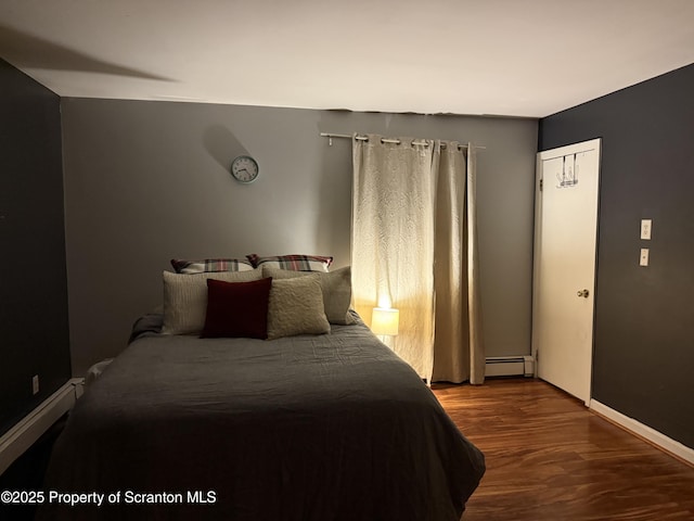 bedroom featuring a baseboard radiator, baseboards, and wood finished floors