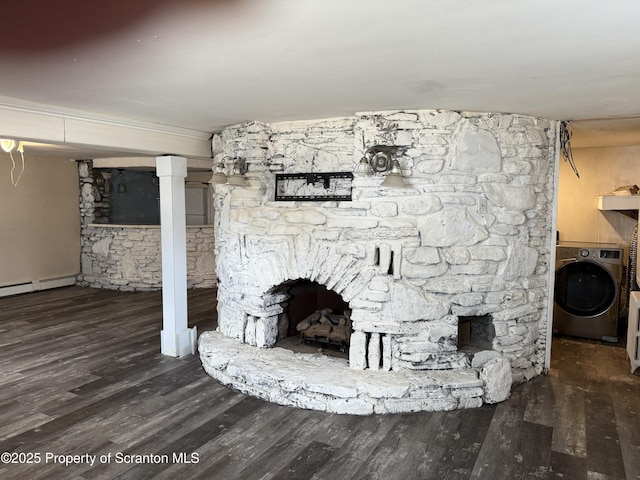 unfurnished living room with a stone fireplace, washer / clothes dryer, wood finished floors, and a baseboard heating unit