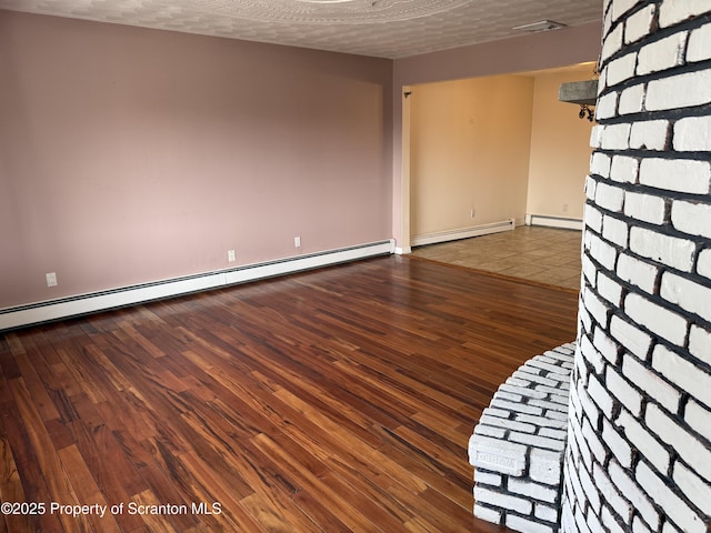 empty room featuring a baseboard heating unit, wood finished floors, and a textured ceiling