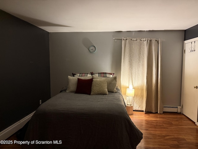 bedroom with a baseboard heating unit and wood finished floors