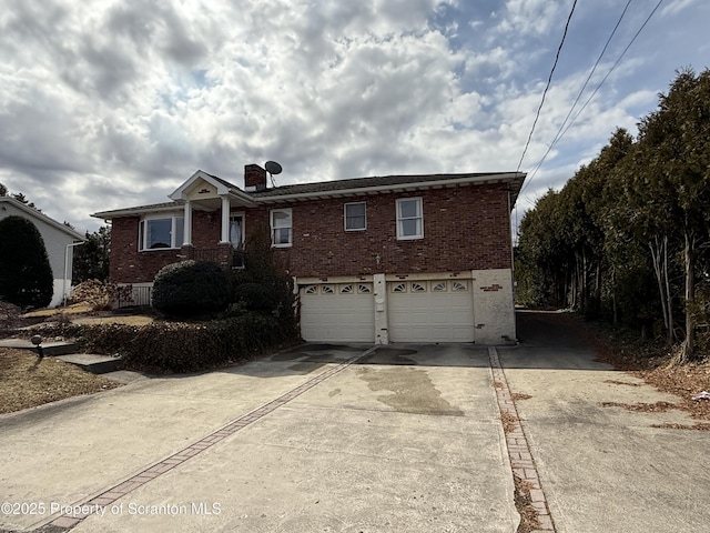 view of front of home with brick siding, an attached garage, concrete driveway, and a chimney