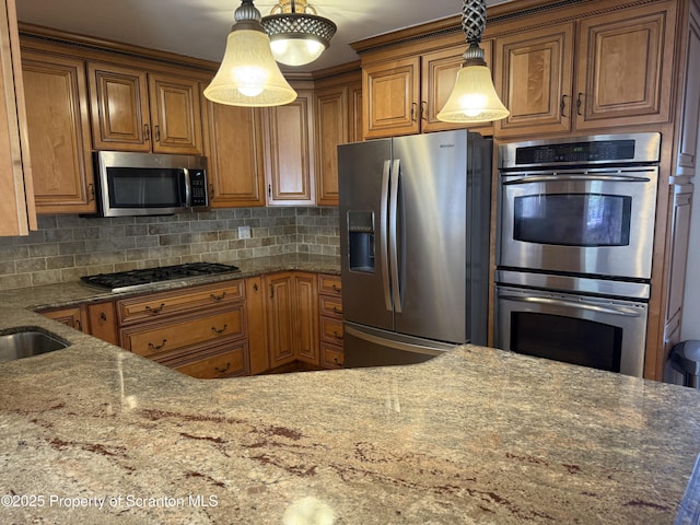 kitchen with stainless steel appliances, decorative backsplash, brown cabinetry, and dark stone counters