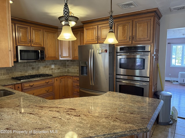 kitchen with tasteful backsplash, brown cabinetry, visible vents, and appliances with stainless steel finishes