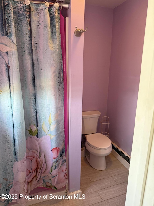 full bathroom with toilet, a baseboard heating unit, baseboards, and wood finished floors