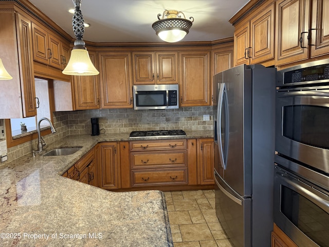 kitchen featuring backsplash, brown cabinetry, appliances with stainless steel finishes, and a sink