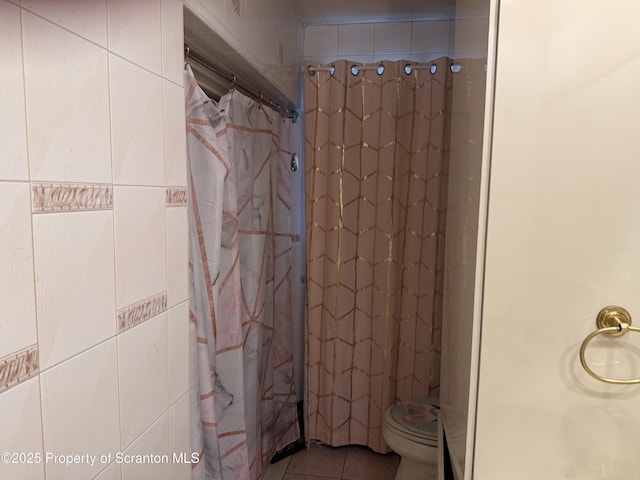 bathroom with tile patterned floors, toilet, a shower with shower curtain, and tile walls