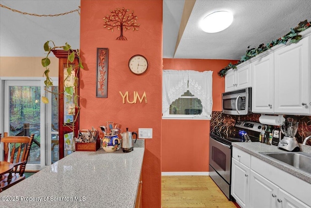 13 S Lehigh River Dr, Clifton Twp, PA 18424 - kitchen featuring appliances with stainless steel finishes, a sink, light wood-type flooring, light countertops, and backsplash