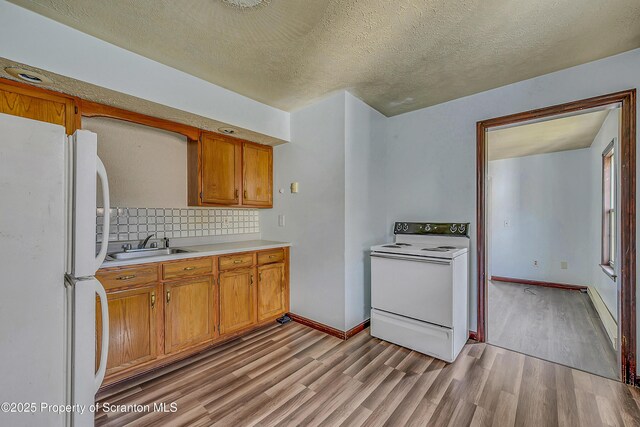 kitchen featuring light countertops, light wood-type flooring, backsplash, and white appliances