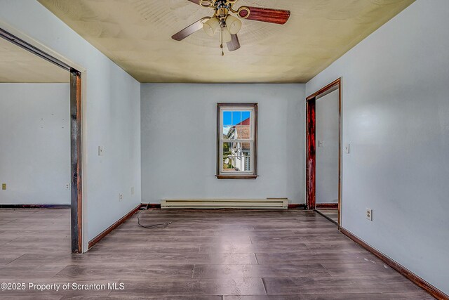 spare room featuring baseboards, ceiling fan, wood finished floors, and a baseboard radiator
