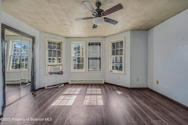 spare room with ceiling fan, a baseboard heating unit, and wood finished floors