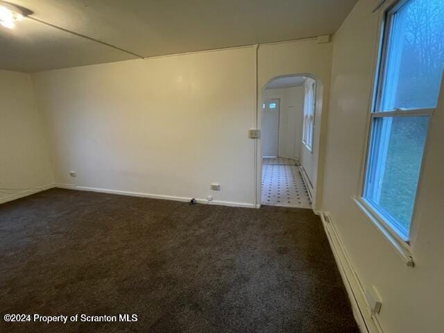 unfurnished room featuring baseboard heating and dark carpet