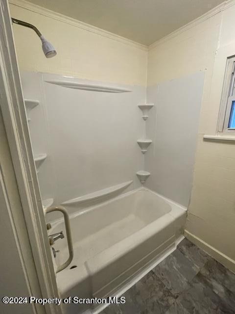 bathroom featuring crown molding and washtub / shower combination