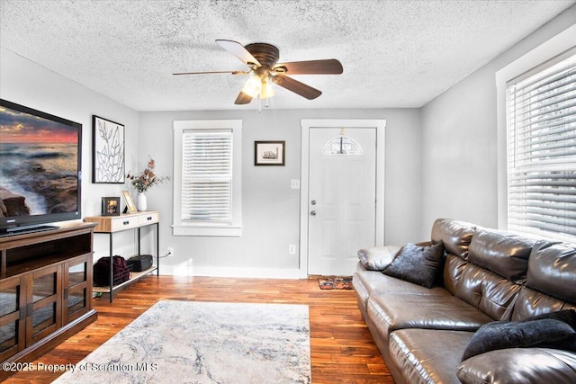 living room featuring a textured ceiling, light wood-type flooring, and ceiling fan