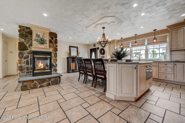 214 Oak St, Dunmore, PA 18512 - kitchen featuring cream cabinets, a chandelier, a stone fireplace, a kitchen island, and a warming drawer