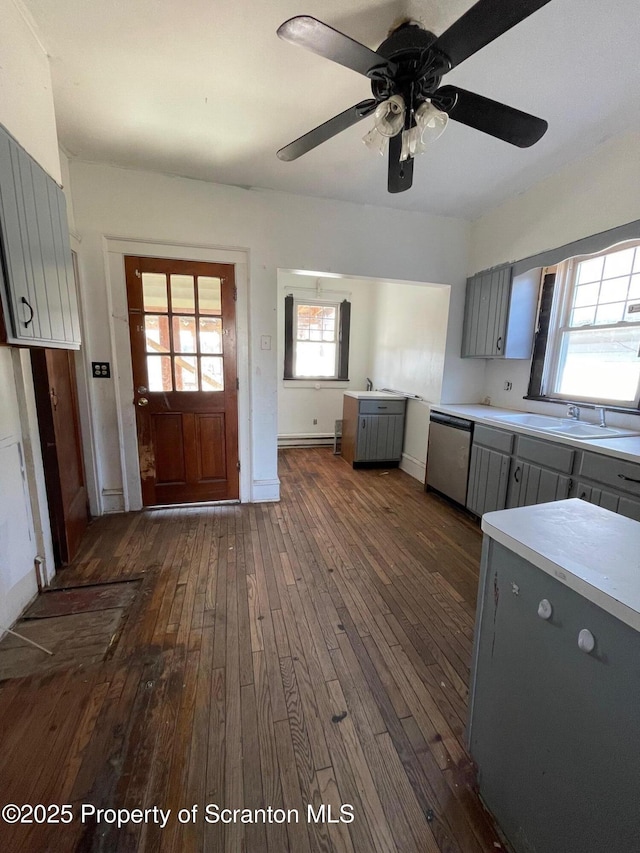 kitchen featuring stainless steel dishwasher, light countertops, dark wood-type flooring, and gray cabinetry