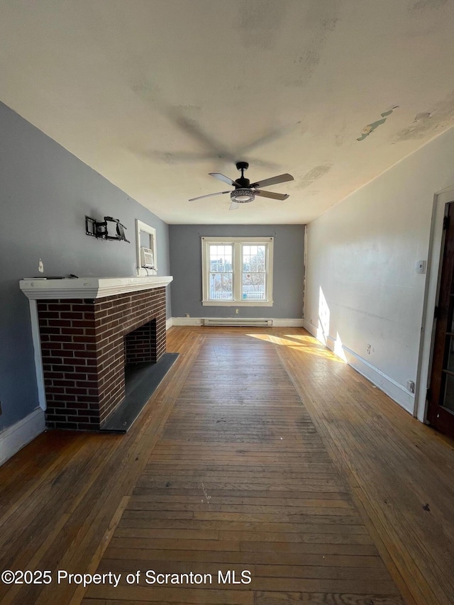 unfurnished living room with dark wood-style floors, a brick fireplace, a baseboard heating unit, and baseboards